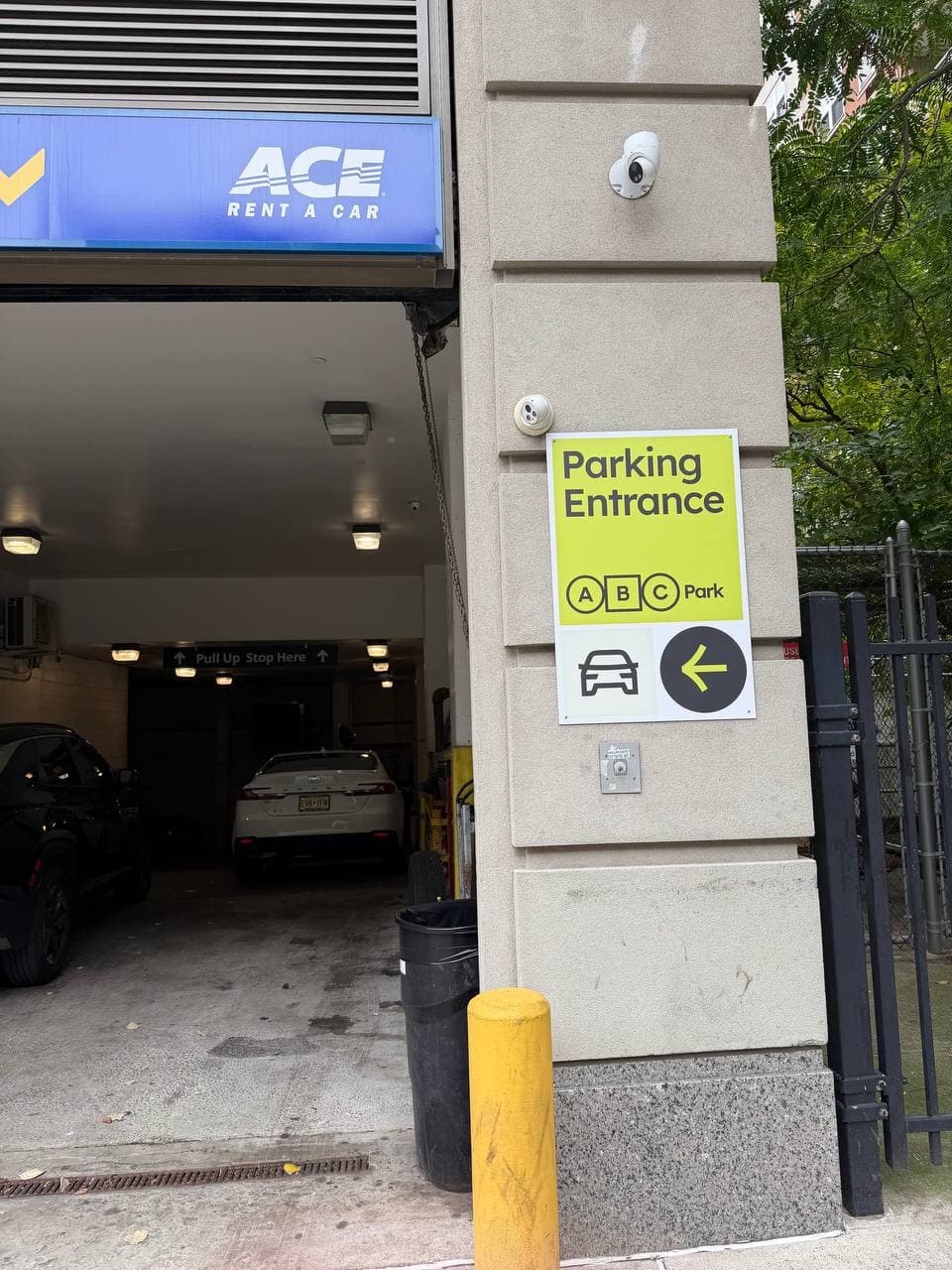 Close-up of the lime ABC Park Parking Entrance sign and its left-pointing arrow.
